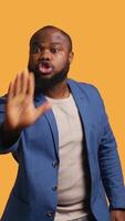 Vertical Stern african american man doing stop hand gesture sign. Annoyed BIPOC person doing firm halt sign gesturing, wishing to end concept, isolated over studio background, camera B video