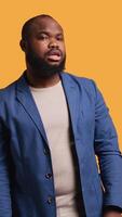 Vertical Smiling man having friendly conversation with friend sitting off camera, isolated over studio background. BIPOC person having fun catching up with mate, having lively discussion, camera B video