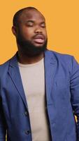 Vertical Smiling man having friendly conversation with friend sitting off camera, isolated over studio background. BIPOC person having fun catching up with mate, having lively discussion, camera A video