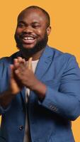 Vertical Approving smiling african american man happily clapping hands, satisfied with accomplishments. BIPOC person cheering, doing praising gesture, isolated over studio background, camera A video