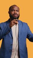 Vertical Portrait of african american lecturer holding monologue using microphone, gesturing with hands, studio background. Expressive BIPOC speaker talking during presentation using mic, camera B video