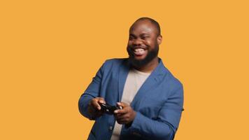 Upset man showing thumbs down sign gesturing holding controller, disapproving of games. Displeased BIPOC person against gaming, doing rejection hand gesture, studio background, camera A video