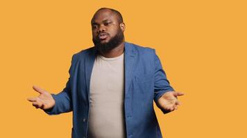 Uncaring man shrugs shoulders, showing indifference and apathy while talking with friend. Careless person doing nonchalant indifferent hand gesturing during conversation, studio background, camera A video