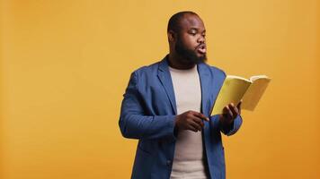 Man reading book aloud, narrating story for audience. Person enjoying literature novel, reciting from pages, entertaining spectators, isolated over studio background, camera B video