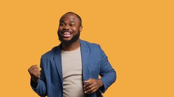 Portrait of joyful cheerful african american man celebrating, showing positive emotions. Delighted BIPOC person thrilled by achievement, cheering and gesticulating, studio background, camera A video