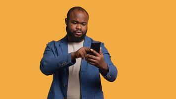 man upprörd efter saknas nödvändig pengar medan påfrestande till köpa grejer uppkopplad på smartphone. ledsen person ser på debitera kort efter få transaktion avvisade på telefon, studio bakgrund, kamera en video