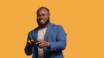 Joyous BIPOC gamer celebrating after winning gaming console game, studio background. Delighted man bragging after being victorious in game, defeating all enemies using gamepad, camera A video