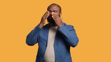 African american man covering eyes, ears and mouth with hands, imitating the three wise monkeys. BIPOC person doing don t see, don t hear and don t speak gesturing concept, studio background, camera A video