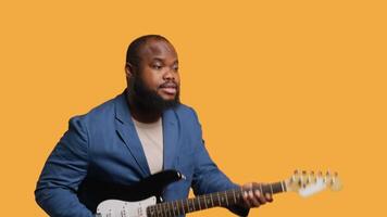 Man holding guitar, excited to perform rock tunes during concert, isolated over studio background. Jolly artist performing metal songs on electric musical instrument, camera A video