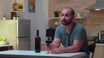 Lonely husband drinking a glass of wine at home. Unhappy person suffering of migraine, depression, disease and anxiety feeling exhausted with dizziness symptoms having alcoholism problems. video