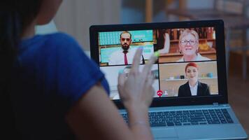 libero professionista avendo conferenza a notte con squadra seduta su divano utilizzando il computer portatile. a distanza lavoratore discutere a in linea incontro, consulenza con colleghi utilizzando chiamata e webcam Lavorando a partire dal casa video