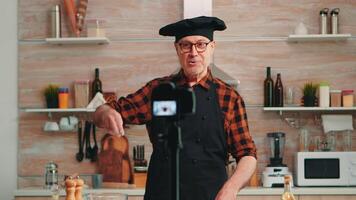 positif chef enregistrement dans cuisine une Nouveau recette pour canaliser. retraité blogueur boulanger influenceur en utilisant l'Internet La technologie communicant, tournage, bloguer sur social médias avec numérique équipement video