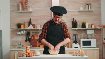 padeiro homem usando farinha para saboroso tradicional receita dentro casa cozinha Falando às Câmera. aposentado blogueiro chefe de cozinha influenciador usando Internet tecnologia comunicando em social meios de comunicação com digital equipamento video