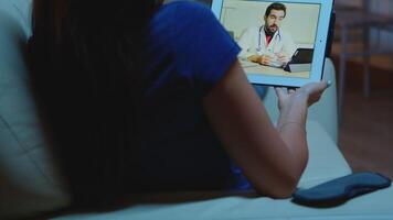 Young woman talking with doctor on webcam using tablet video