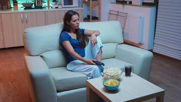 Nervous woman with television remote control sitting on the sofa. Bored, angry lonely lady relaxing watching tv lying on comfortable couch holding controler searching a movie changing the channels. video