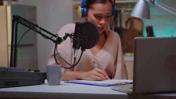 Presenter writing on clipboard and wearing headphones during podcast recording using professional microphone. Creative online show On-air production internet broadcast host streaming live content, recording digital social media communication video