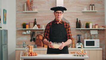 velho homem vestindo bonete enquanto explicando Comida preparação receita olhando às Câmera. aposentado blogueiro chefe de cozinha influenciador usando Internet tecnologia comunicando em social meios de comunicação com digital equipamento video