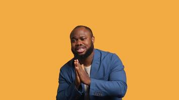 African american man putting hands together in begging gesture, making wish, isolated over yellow studio background. BIPOC person asking for something, praying and hoping, camera A video