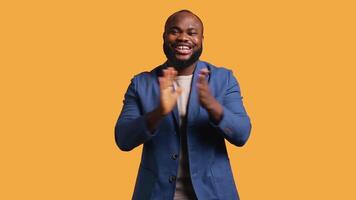 Approving smiling african american man happily clapping hands, satisfied with accomplishments. BIPOC person cheering, doing praising gesture, isolated over studio background, camera B video