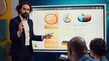 Financial analyst briefing his team about new company objectives, making budget and sales presentation with interactive board. Specialist addressing resource allocation and project planning. Camera A. video