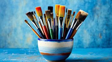 AI generated Vibrant paintbrushes in a bowl against a textured blue backdrop, symbolizing creativity photo