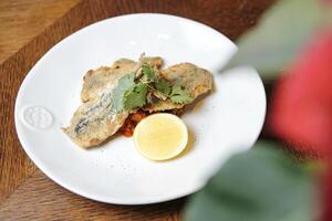 White Plate With Fried Fish and Lemon Slice photo