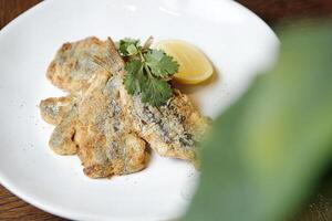 Freshly Cooked Fish With a Slice of Lemon on a White Plate photo