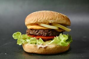 jugoso hamburguesa con lechuga y tomate en negro superficie foto