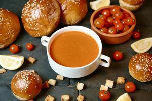 taza de tomate sopa con un pan y Cereza Tomates foto