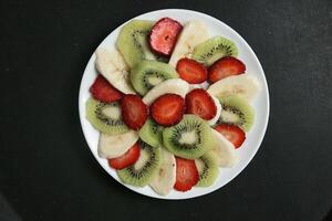 blanco plato con rebanado kiwi y fresas foto