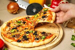 Person Taking a Slice of Pizza at a Pizzeria photo