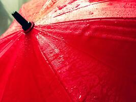 rojo paraguas textura con agua gotas para lluvioso día antecedentes. foto