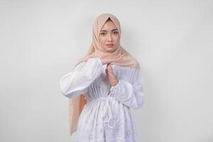 retrato de joven asiático musulmán mujer vistiendo blanco vestir y hijab haciendo hora fuera gesto con manos y grave cara terminado aislado blanco antecedentes foto
