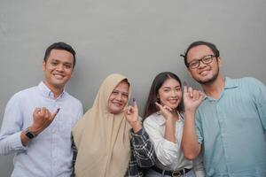 Portrait of excited Indonesian family showing the little finger dipped in purple ink after voting for general election or Pemilu for president and government, isolated grey background photo