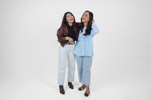 Two young Asian women expressing their happiness, isolated by white background. Friendship concept. photo