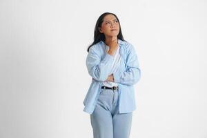 un pensativo asiático mujer vistiendo azul camisa es imaginando su pensamientos, aislado por blanco antecedentes. foto