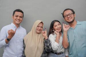 Portrait of excited Indonesian family showing the little finger dipped in purple ink after voting for general election or Pemilu for president and government, isolated grey background photo