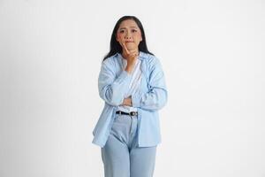 A thoughtful Asian woman wearing blue shirt is imagining her thoughts, isolated by white background. photo