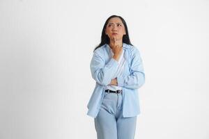 A thoughtful Asian woman wearing blue shirt is imagining her thoughts, isolated by white background. photo