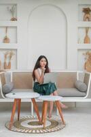 Thoughtful young woman using laptop while sitting on a sofa focused and in deep thought, working on holiday photo