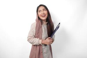 Portrait of Asian Muslim woman in headscarf veil hijab standing and smiling happily while holding a document map. Ramadan concept photo