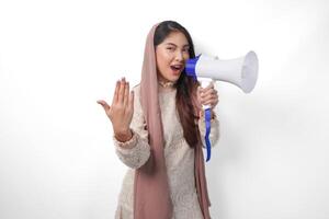 energético asiático musulmán mujer vistiendo velo hijab gritos a megáfono mientras levantamiento mano como atractivo o vamos Vamos gesto. Ramadán y eid Mubarak concepto foto