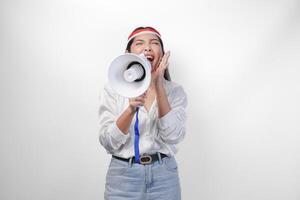 Energetic Asian woman in casual formal outfit wearing country flag headband while holding and shouting at megaphone, standing on isolated white background photo