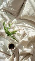 A Cup of Coffee on Bed Next to Vase of Flowers photo