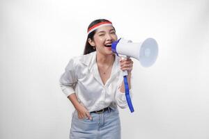 Energetic Asian woman in casual formal outfit wearing country flag headband while holding and shouting at megaphone, standing on isolated white background photo