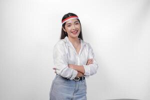 Young Asian woman in casual outfit standing with crossed arms and flag headband showing smile and expression full of confidence photo