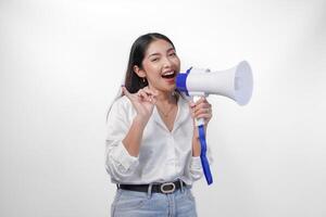 emocionado asiático mujer en casual formal atuendo participación y gritos a megáfono, señalando pequeño dedo sumergido en púrpura tinta después votación para Indonesia elección, en pie en aislado blanco antecedentes foto