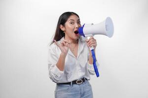 Excited Asian woman in casual formal outfit holding and shouting at megaphone, pointing little finger dipped in purple ink after voting for Indonesia election, standing on isolated white background photo