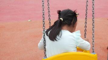 uma criança tendo Diversão em uma balanço em a Parque infantil dentro público parque. video