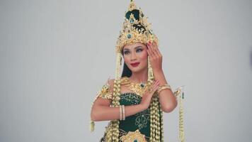 Elegant woman in traditional Asian attire with intricate gold jewelry posing against a neutral background. video